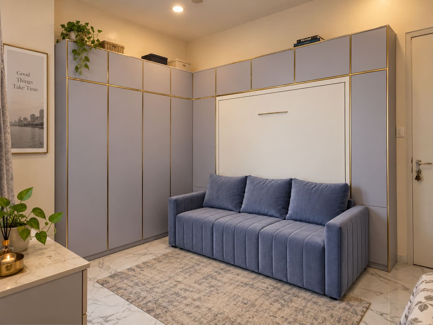 Lavender-grey full-wall corner unit with brass trim: wardrobes on the left run, Dwalsbed closed behind a blue three-seater sofa on the right.